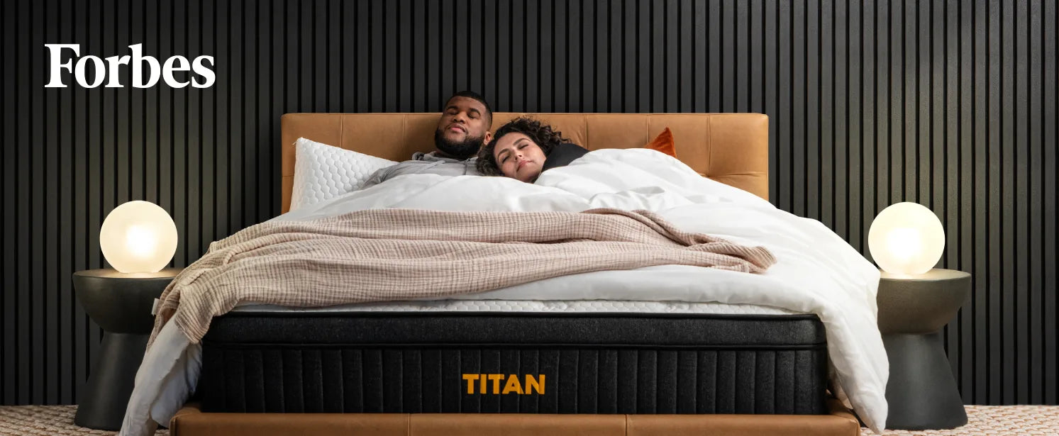 Forbes text over an image of a man and woman sleeping on a Titan Plus Luxe mattress