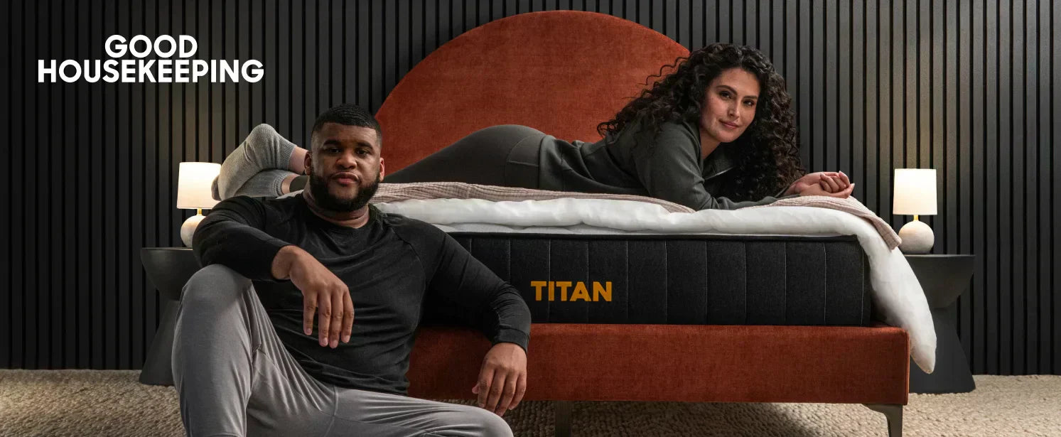 woman laying across a Titan mattress with a man sitting in front of the mattress on the floor