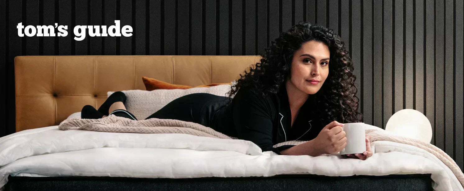 Woman holding a coffee mug laying across a Titan mattress
